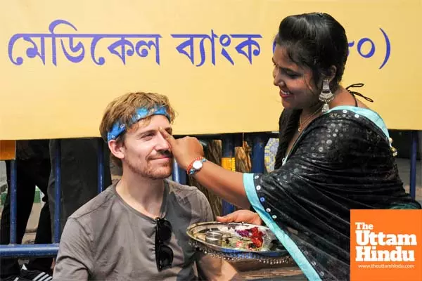 A woman applies a traditional tilak to a tourist on the occasion of the Bhai Dooj festival