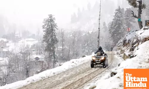 Baramulla: A person rides an all-terrain vehicle on a snow-covered road amid heavy snowfall