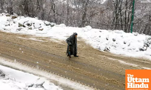 Baramulla: An elderly man walks past a snow-covered road amid heavy snowfall