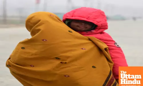 Prayagraj: A woman holds her child, both wrapped in warm clothes
