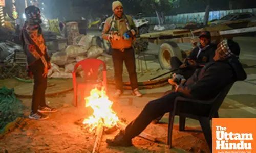 Prayagraj: People sit around a bonfire to keep themselves warm on a cold morning