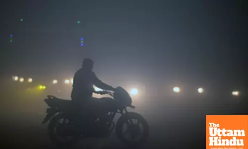 Noida: A man rides his bike through dense fog on a chilly winter morning