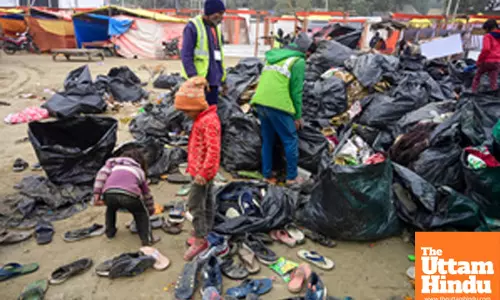Prayagraj: Family members of a worker find for coins at the Triveni Sangam