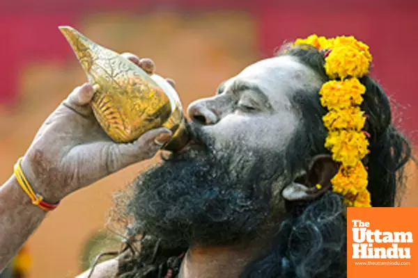 Title : Prayagraj: A Sadhu (Holy Man) blows a shankh (conch shell) at the Triveni Sangam