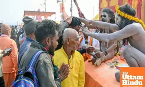 Prayagraj: A Naga Sadhu (Holy Man) applies Tilak to a man after taking a holy dip at the Triveni Sangam