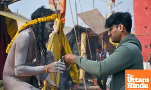 Prayagraj: A Naga Sadhu (Holy Man) ties sacred thread to a man after taking a holy dip at the Triveni Sangam