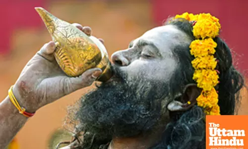 Title : Prayagraj: A Sadhu (Holy Man) blows a shankh (conch shell) at the Triveni Sangam