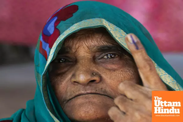 An elderly voter shows her inked finger after casting her vote for the Delhi Assembly Elections