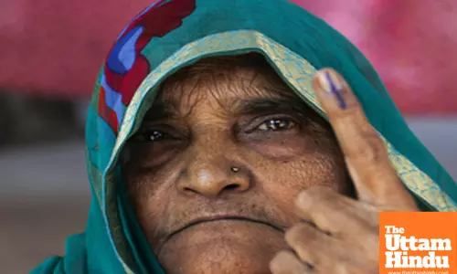 An elderly voter shows her inked finger after casting her vote for the Delhi Assembly Elections