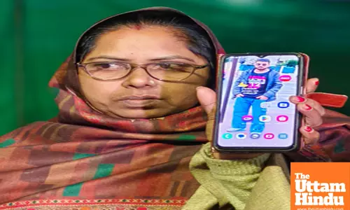A woman holds a phone displaying a photo of a relative, among the Indian immigrants deported from the US