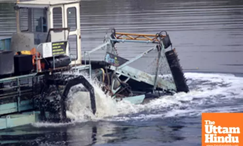 A trash skimmer operates to remove garbage from the Yamuna River